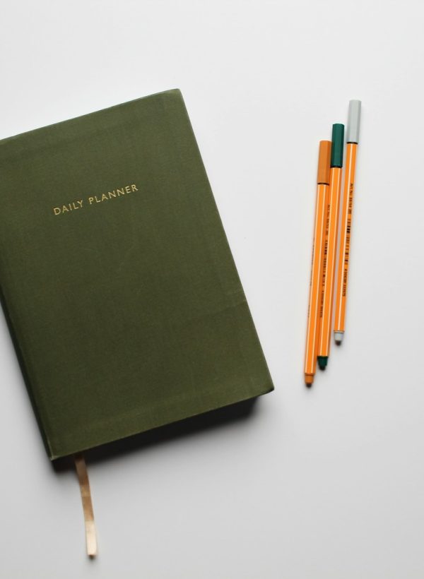 green book with pencils on white table